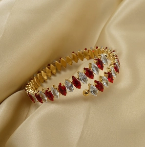 Detail of 18K gold open bangle with red and white marquise-cut zircon stones on satin