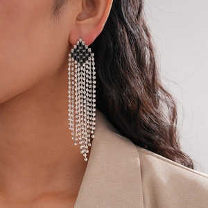 Detailed view of silver diamond fringe earrings with black geometric accents on a model