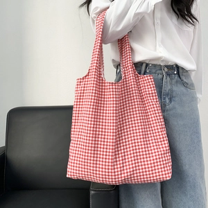 Borsa tote in tela a quadretti bianchi e rossi indossata da una modella come borsa a spalla