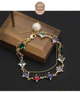 Detail of vintage gold bracelet with colorful oval gemstones and a large white pearl drop