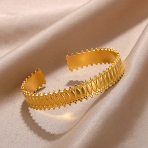 Detail of matte gold open cuff bracelet featuring relief oval patterns and beaded edges
