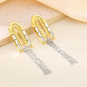 Macro shot of gold arch earrings with rectangular crystals and silver chain tassels