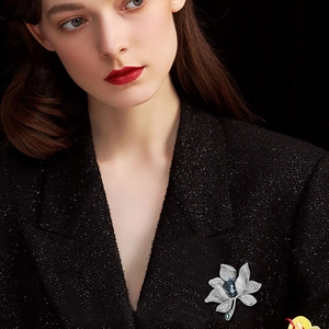 Luxuriöse Blumenbrosche mit blauem Kristall und weißen Zirkonia auf schwarzem Tweed-Sakko