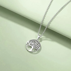 Polished silver Tree of Life circular pendant necklace for women on light green surface