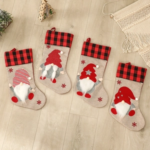 Set of 4 linen Christmas stockings with gnome appliques on light wood floor background