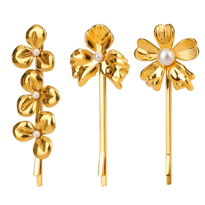 Détail de trois pinces à cheveux fleurs plaquées or 18 carats avec perles sur fond blanc