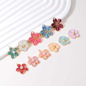 Macro shot of colorful enamel flower charms with gold metal bases and faux pearl centers