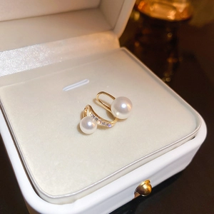 Detail of twisted gold ear cuff with double pearls and zircons in a beige jewelry box