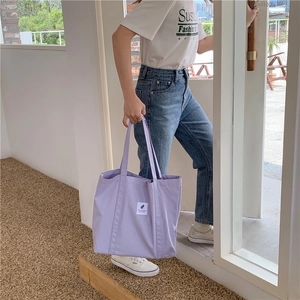 Lifestyle shot of light purple canvas tote bag carried by model on outdoor steps