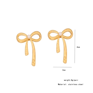 Detailed view of golden bow earrings with pearl center and textured stainless steel finish