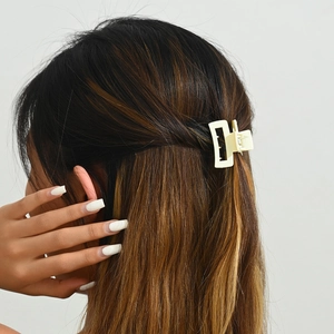 Détail d'une pince à cheveux rectangulaire mate crème de 2,5 cm sur une demi-queue