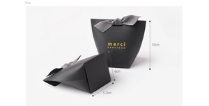 Detail of black trapezoid gift box with grey ribbon and gold merci beaucoup text