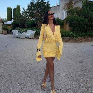 Abito corto giallo vivace con profondo scollo a V, maniche lunghe e gonna a pieghe