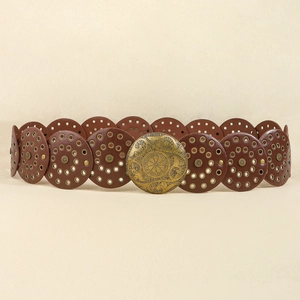 Dettaglio di cintura western in pelle marrone con fori circolari e fibbia in ottone inciso