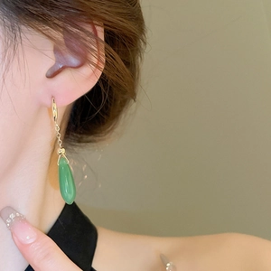Close-up of green teardrop earring with gold-plated silver hook on model's ear