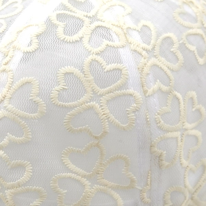 Close-up of mesh lace fabric featuring heart embroidery and delicate mesh texture