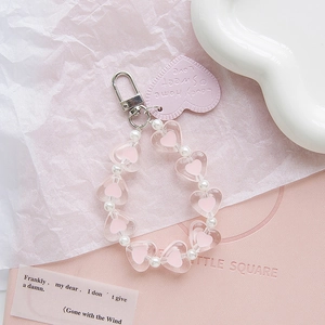 Dettaglio ciondolo a cuore rosa con perle finte e targhetta in pelle per borse