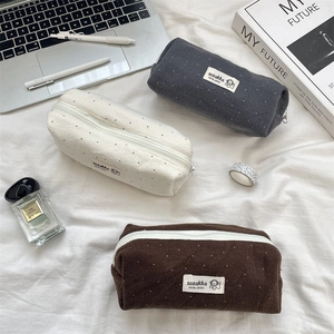 Estuches minimalistas de lana a lunares en tres colores en un escritorio elegante