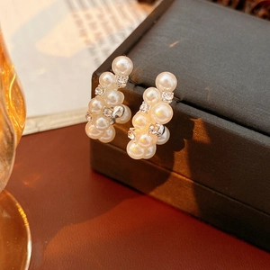 Primer plano de pendientes de racimo de perlas con circonitas en baño dorado