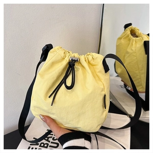 Detailed close-up of yellow nylon drawstring bucket bag with adjustable black shoulder strap