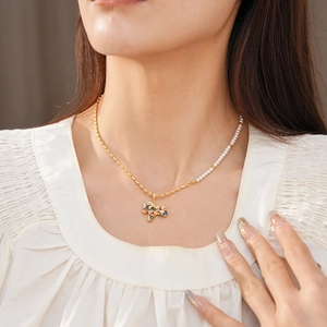 Detail of vintage gold horse necklace with pearls and colorful zircons on a model