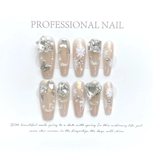 Elegant nude pink press-on nails with white floral patterns and sparkling crystals