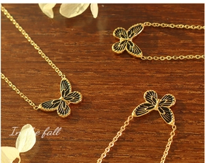 Macro detail of Bohemian gold plated butterfly pendants with black enamel texture