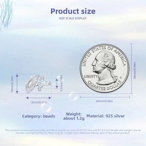 Detailed size view of silver whale charm with blue stones next to a quarter coin
