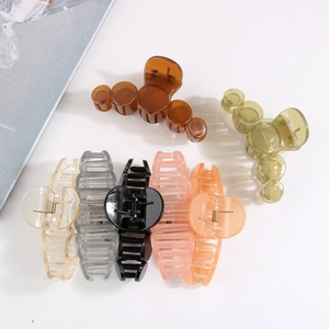 Flat lay of multiple colorful PS material hair claws in brown green and pink on white