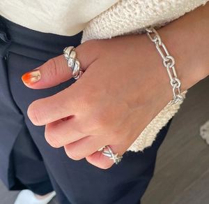 Close-up of S925 sterling silver chain bracelet and chunky textured rings on model hand