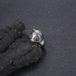 Macro close-up of a silver panda head ring on rustic wood with polished metallic finish
