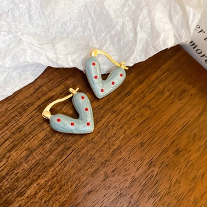 Detail of blue heart hoop earrings with red polka dots and golden metal clasp