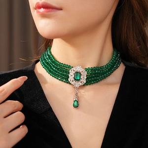 Detail of vintage multi-layer emerald green beaded choker with ornate silver pendant
