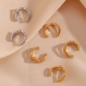 Macro detail of wave patterned C-shape ear clips in gold and silver finish