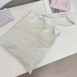 Detail of light blue canvas tote bag with orange cat prints and woven brand label