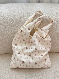 Cream bubble fabric shoulder bag with cute brown bear prints on a cozy beige sofa