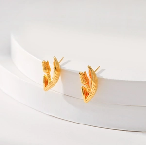 Bohemian 18K gold tulip stud earrings elegantly placed on a white stepped display