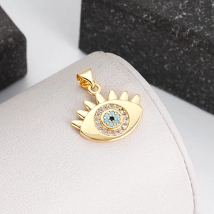 Detailed close-up of gold evil eye pendant with blue and white zircon on display