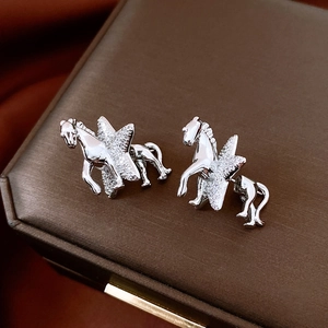 Detail of silver horse and star earrings with cubic zirconia on a jewelry box