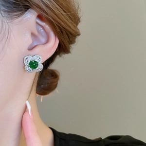 Close-up of vintage emerald flower stud earring with micro-diamond setting on a model