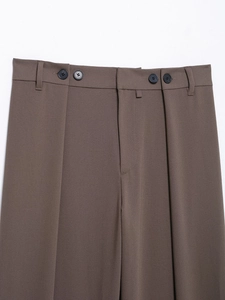 Detailed macro view of brown trousers waist featuring double button design and belt loops