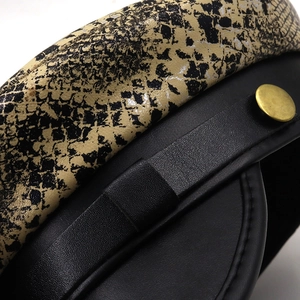 Detailed macro shot of vintage military hat with snake print fabric and black leather brim
