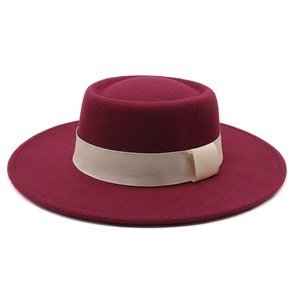 Macro view of burgundy wool felt wide brim boater hat with ivory ribbon decoration