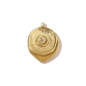 Macro shot of gold sunburst pendant with translucent opal center on white background