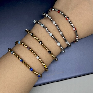 Detailed view of layered evil eye beaded bracelets in gold and silver finish
