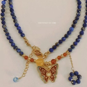 Close-up of a bohemian beaded necklace with a colorful painted butterfly pendant