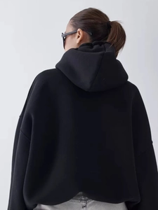Detailed back view of an oversized black hoodie showing the thick cotton fabric and loose fit