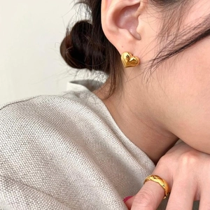 Polished gold 3D heart stud earrings and quilted pattern band ring set on a model