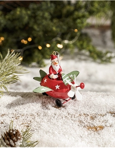 Detail of Santa Claus in a vintage metal airplane hanging ornament on a snowy branch