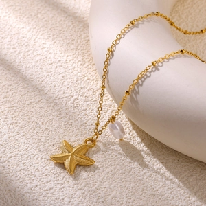 Macro view of golden starfish pendant with a white pearl on a stainless steel chain